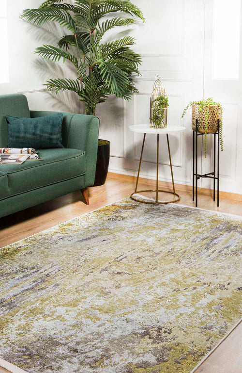 Load image 1 in gallery view. A modern living room features a green sofa, leafy plant, two side tables with decorative plants, and the Color Splash - Washable Rug - JR146 (Custom Size) in light tones on a wooden floor. Sunlight streams through the windows.