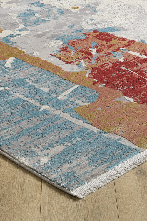 Load image 1 in gallery view. A close-up of the Colorful Chaos Premium Rug - M313P shows its abstract blue, red, gold, and white patterns, short fringe edging, and placement on a light wood floor.