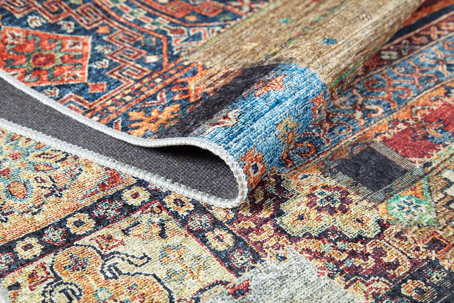 A close-up of the Colorful Composition - Washable Rug - JR5107 (Custom Size) shows its folded corner, intricate stitched edge, and bold geometric and floral motifs in red, blue, beige, and yellow—perfect for high-traffic areas.