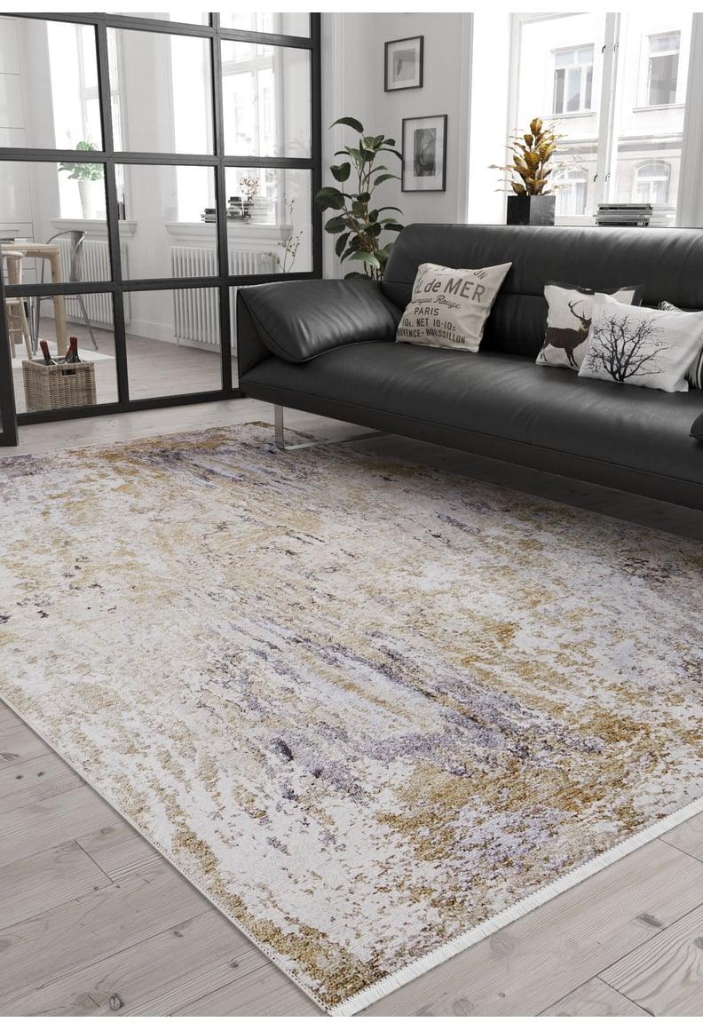 Modern living room with a black sofa, decorative pillows, plants, and city views through large windows. The 'Contemporary Canvas - Washable Rug - JR145' in beige and purple highlights the wooden floors; ideal for high-traffic areas with a glass divider.