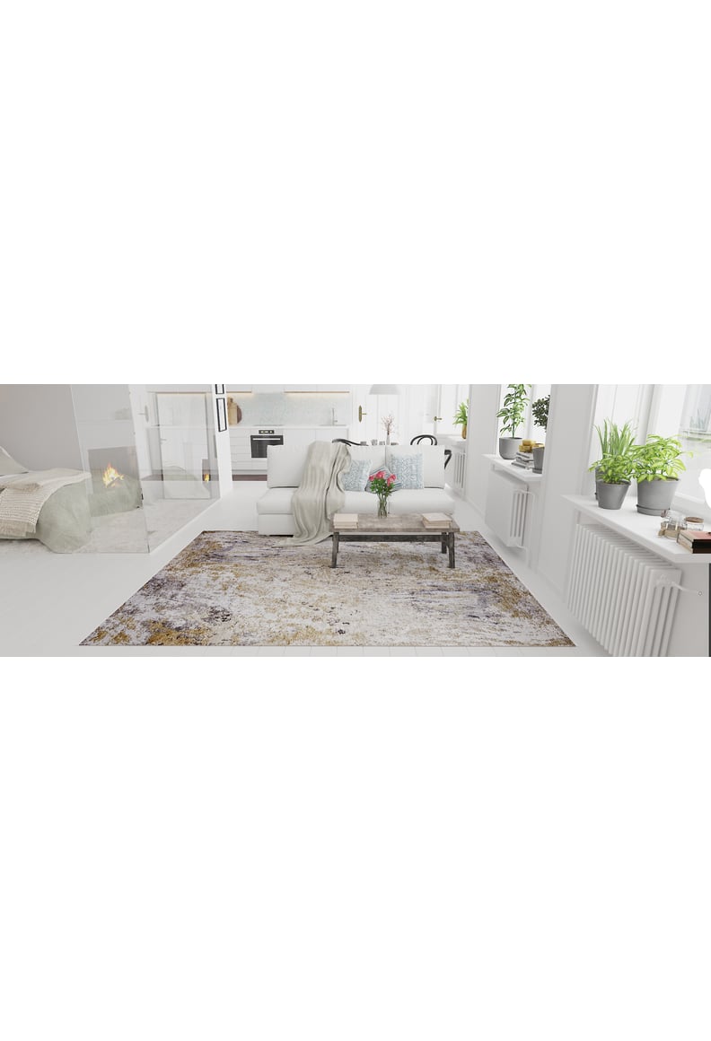 A bright, modern living room with large windows, white walls, a cozy fireplace, and neutral furniture showcases the Contemporary Canvas - Washable Rug - JR145 (Custom Size), ideal for high-traffic areas, with green plants on the sill and a blanket over a chair.