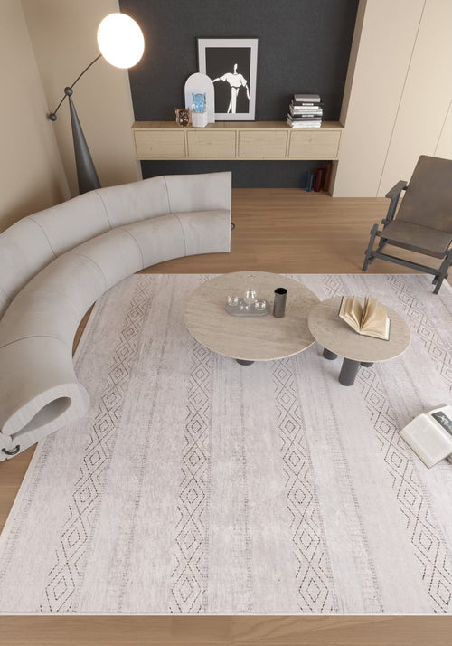 Load image 1 in gallery view. A modern living room features a curved gray sofa, two round coffee tables with books and glassware, a floor lamp, a wall-mounted console with decor and art, and the Contemporary Coordinates - Washable Rug - JR750 (Custom Size) ideal for high-traffic areas.
