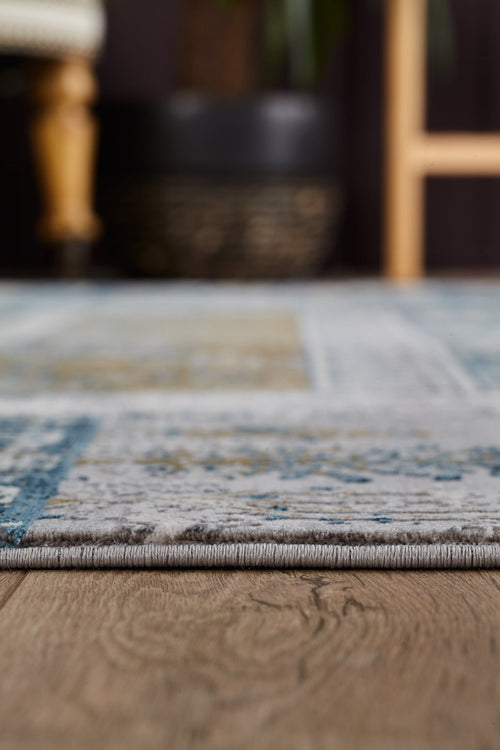 Load image 1 in gallery view. Close-up view of the Cool Nomadica Premium Rug - M366B on a wooden floor, with a chair edge and potted plant softly blurred in the background.