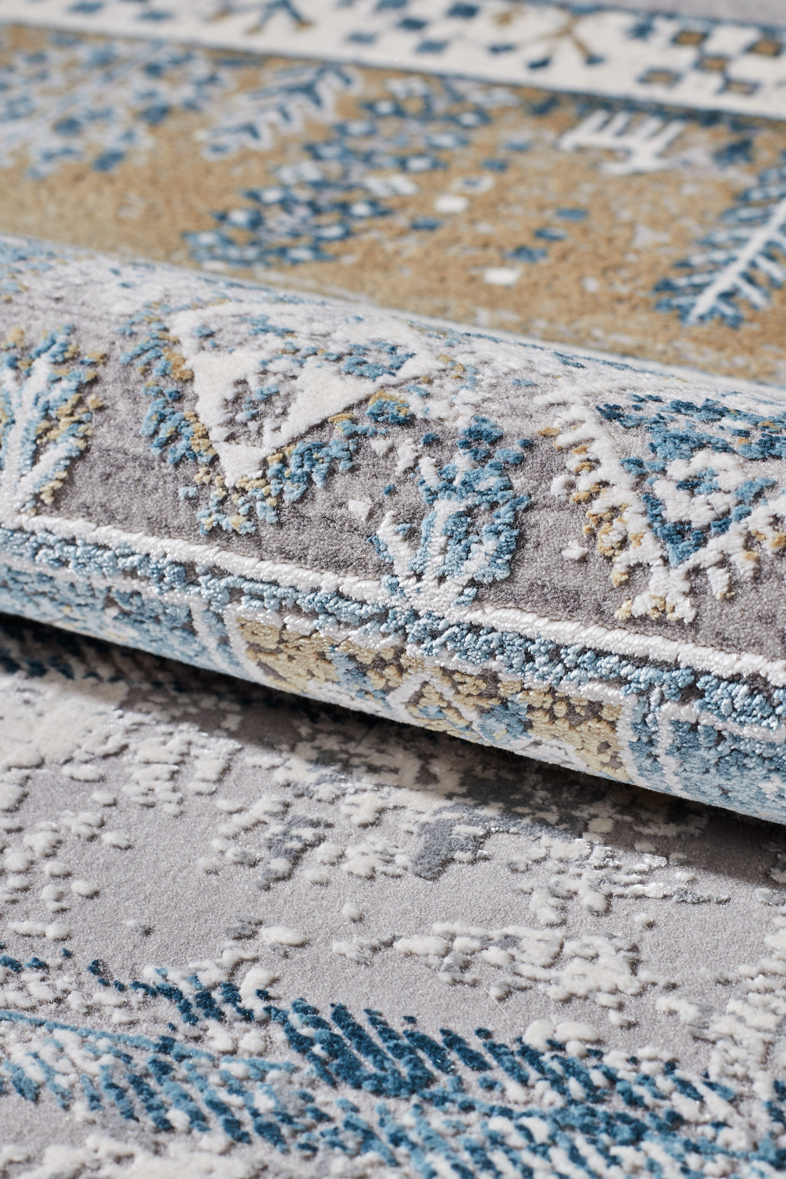 The Cool Nomadica Premium Rug - M366B features blue, beige, and white geometric and floral patterns with a distressed finish, textured raised surface, and detailed machine-made weaving.