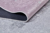 A close-up of the Cosmic Naptime - Machine-Washable Rug JRC032 (Custom Size) in light purple shows its corner lifted to reveal a dark non-slip backing, with the flat weave rug placed on a light gray textured floor.