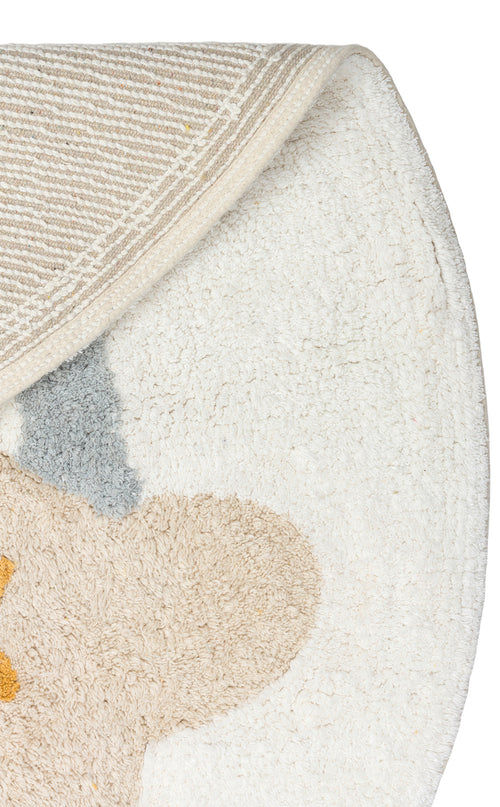 Load image 1 in gallery view. A close-up of the Cozy Puzzle - Washable Shaggy - CBN07 shows its round, mostly white surface with beige, gray, and yellow abstract shapes. Ideal for kids’ rooms, this rug is washable and features a striped underside with a folded corner.