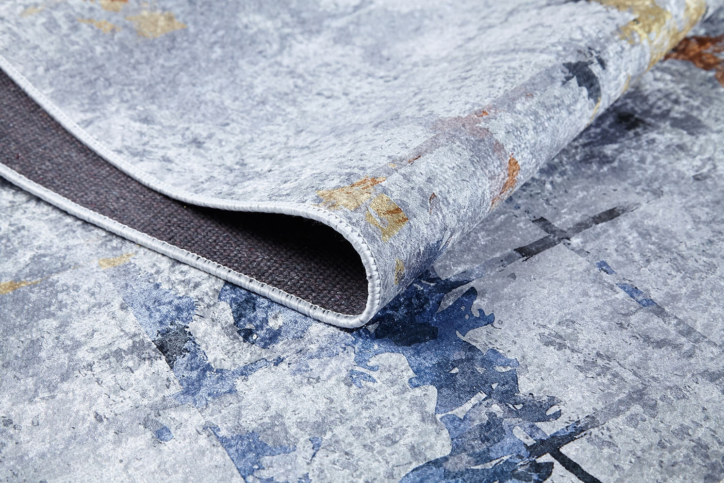 A close-up of the Cross Country - Washable Rug - JR1753 (Custom Size) in blue, featuring a mottled blue, gray, and beige abstract pattern with a textured surface and dark backing—perfect for high-traffic areas.