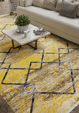 A modern living room features a light-toned sofa, gray and white cushions, a marble coffee table with accents, and the Crossed Connections - Washable Rug - JR1181 (Custom Size) in yellow-gold with a bold geometric black and white pattern.