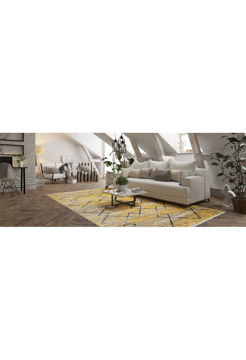 Load image 1 in gallery view. A bright loft living room features a white sofa, neutral pillows, and the Crossed Connections - Washable Rug - JR1181, ideal for high-traffic areas. A coffee table, potted plants, exposed beams, and wood flooring glow with natural light from large windows.