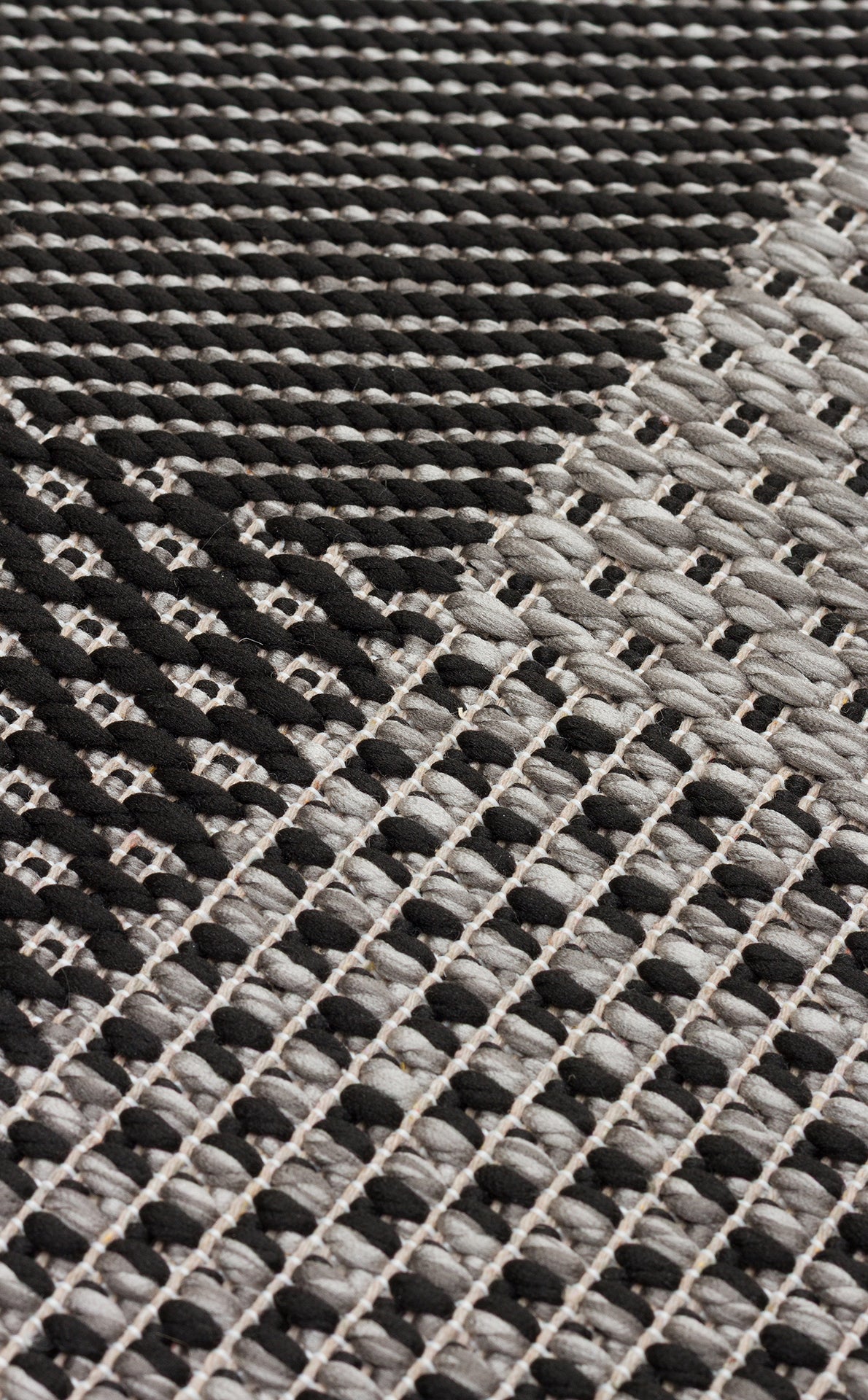 Close-up of the Deep Slate - Kilim - MNO01 rug, showcasing its geometric checkered pattern in black, white, and gray tones with textured intersecting lines and shapes.