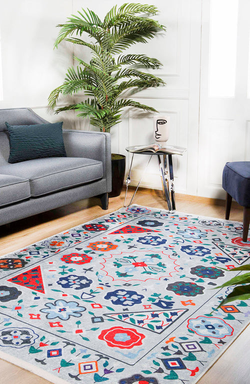 Load image 1 in gallery view. A modern living room with a gray sofa, decorative plant, glass side table with an abstract face vase, and the Desert Drift - Washable Rug - JR1523 (Custom Size)—perfect for high-traffic areas—on a light wooden floor.