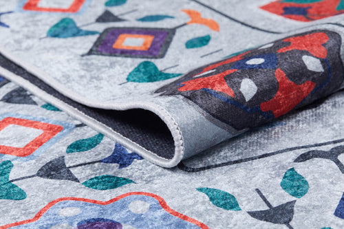 Load image 1 in gallery view. A close-up of the Desert Drift - Washable Rug - JR1523 (Custom Size) shows its vibrant abstract geometric and floral patterns on a light gray background. The folded corner reveals detailed texture and stitching, ideal for high-traffic areas.