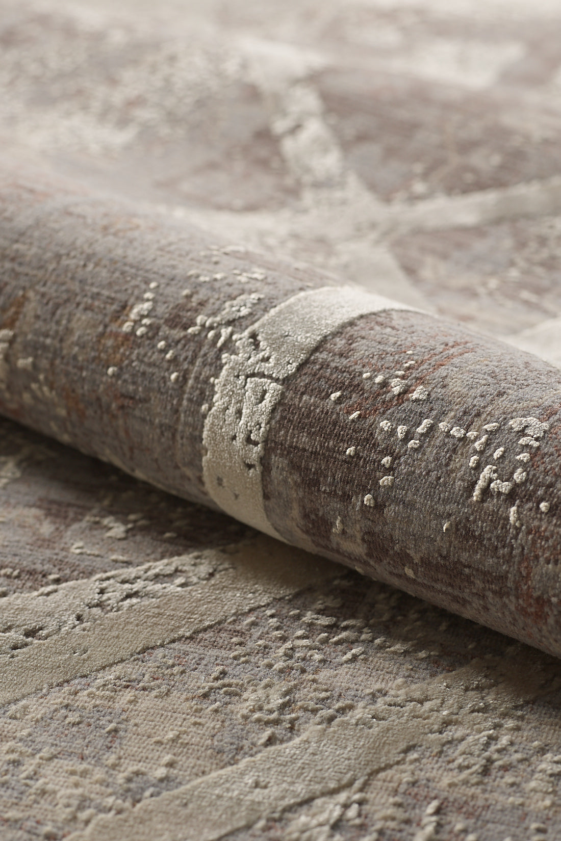 A close-up of the Dominant Lineage Modern Rug - Bright - M633M, featuring rolled, textured geometric patterns in earthy tones with abstract raised detailing and a blend of beige, brown, and taupe.