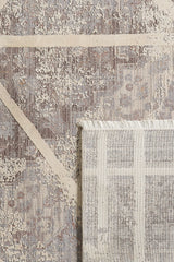 A close-up of the Dominant Lineage Modern Rug - Bright - M633M, featuring abstract beige and gray patterns, with a corner flipped to display the lighter patterned underside and fringe.