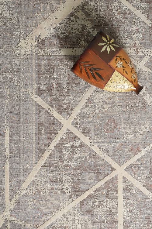 Load image 1 in gallery view. The Dominant Lineage Modern Rug - Bright - M633M features intersecting cream lines on gray for modern elegance, accented by a decorative ceramic vase with floral and leaf motifs in the top right corner.