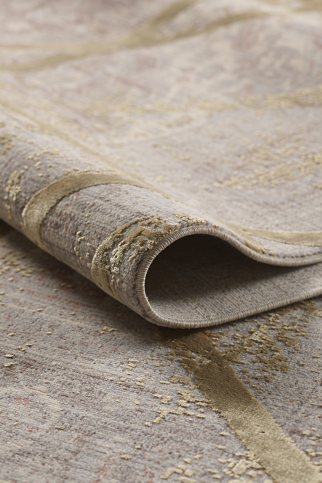 A close-up of the Dominant Lineage Modern Rug - Harvest - M633N showcases its rolled edge, soft texture, and subtle gold and beige patterns in neutral tones.