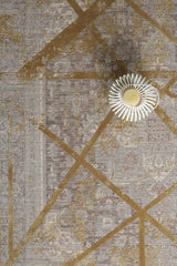 A top-down view of the Dominant Lineage Modern Rug - Harvest - M633N, featuring intersecting gold lines, with a white candleholder containing a candle placed near the upper right side.