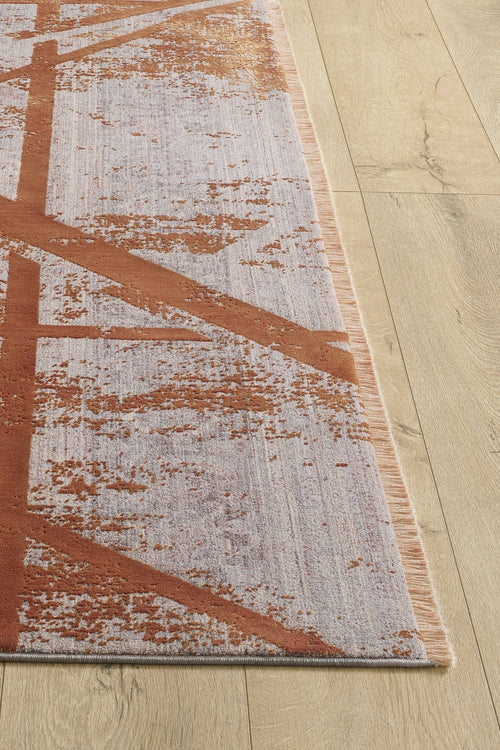 Load image 1 in gallery view. A close-up of the Dominant Lineage Modern Rug - Tangerine (HRD007) displays its abstract rust and light gray pattern on a light wood floor, with one corner revealing the rug’s texture and industrial chic colors.