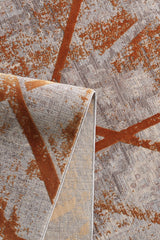 A close-up of the Dominant Lineage Modern Rug - Tangerine (HRD007) shows abstract rust orange and beige geometric patterns on a gray background, with one corner folded to reveal the underside.
