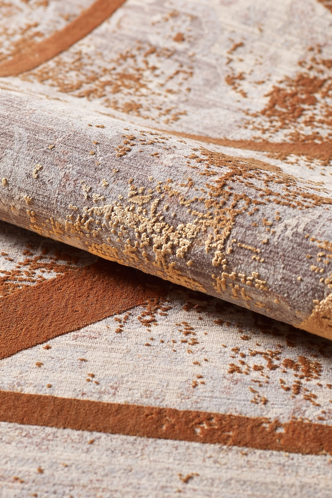 A close-up of the Dominant Lineage Modern Rug - Tangerine (HRD007) highlighting its machine-made abstract pattern in brown, beige, and gold tones with a textured, raised design.