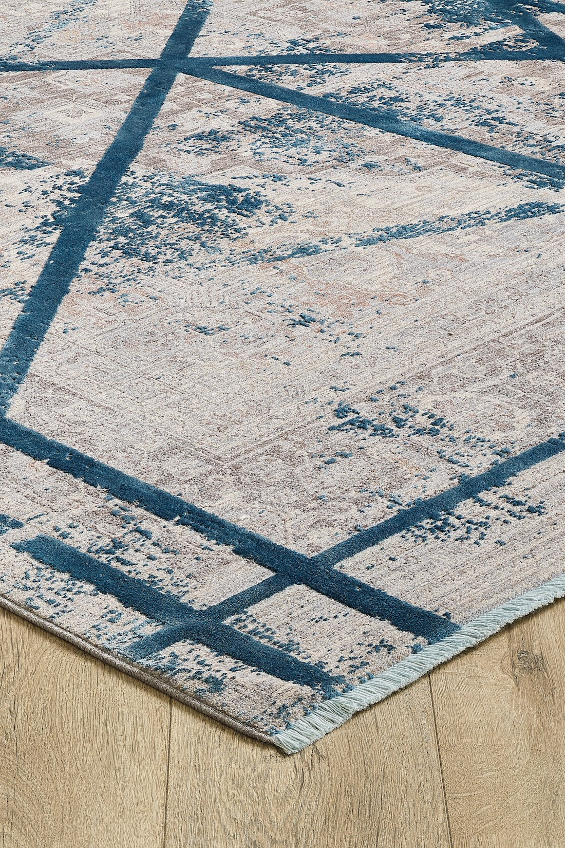 A close-up of the Dominant Lineage Modern Rug - Teal - HRD010, showcasing its modern abstract design in beige, cream, and blue with intersecting teal lines and distressed patterns for an industrial chic look on a light wood floor.