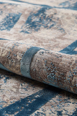 A close-up of the Dominant Lineage Modern Rug - Teal - HRD010, a machine-made rug with a textured surface, showcasing abstract lines and speckles in brown and blue tones.