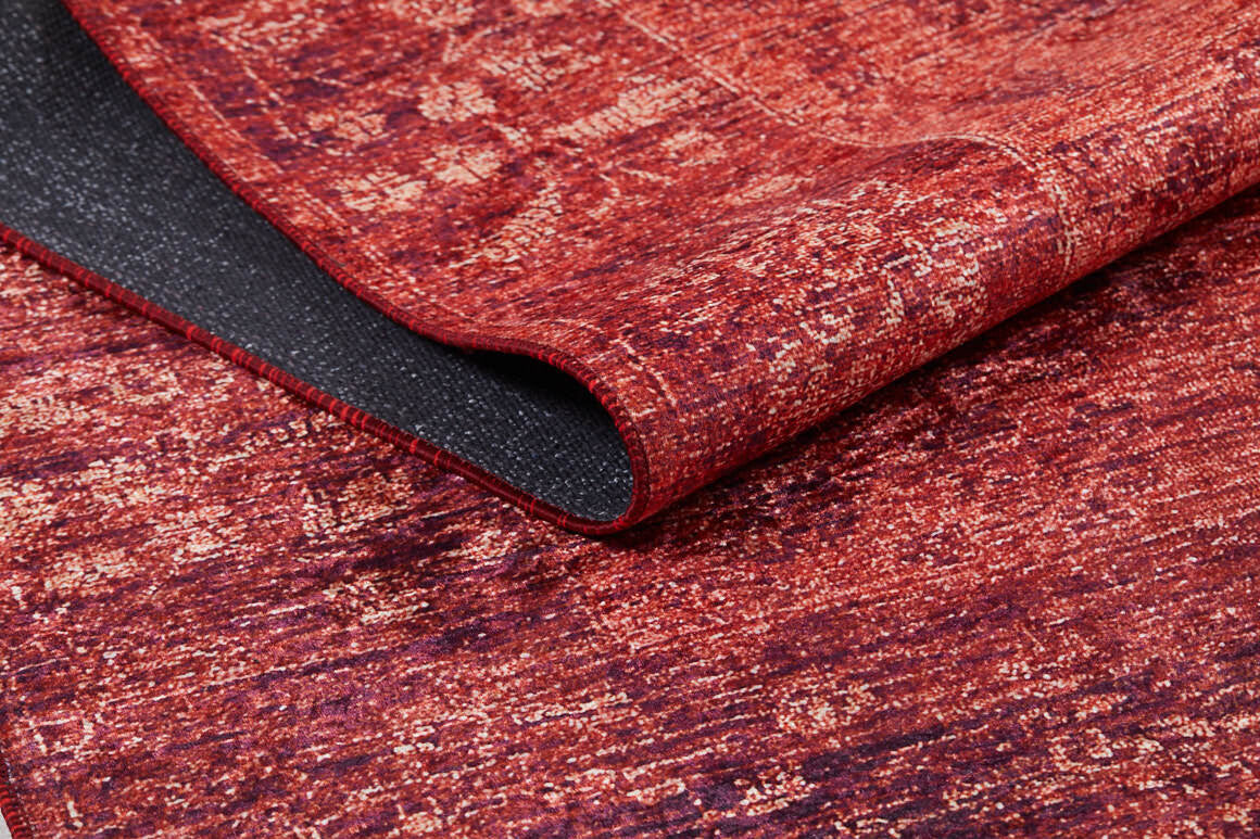The Dynasty Dream - Washable Rug - JR160 (Custom Size) features a textured, slightly distressed red and orange abstract oriental pattern. A folded corner reveals its black non-slip backing, combining style with practical washability.