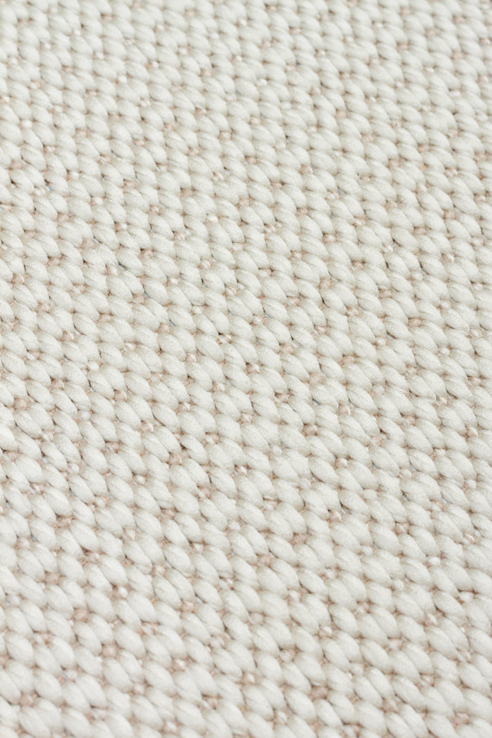 Close-up of the Earth Note - Kilim - MNO04 rug, showcasing its textured, off-white woven fabric with a repeating pattern of thick, tightly interlaced yarns for a timeless design.