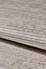 Close-up of the Earthy Textures Neutral Rug - M497J in beige and light brown, featuring subtle horizontal lines and a soft, slightly shiny flat pile. The rug is partially folded, showing its thickness and detailed fabric texture.