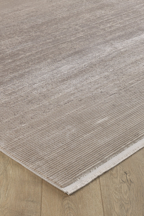 Load image 1 in gallery view. A close-up of the Earthy Textures Neutral Rug - M497J shows its beige flat pile with subtle horizontal lines and a slight sheen, placed on a light wood floor. One minimalist edge is finished with a short fringe.