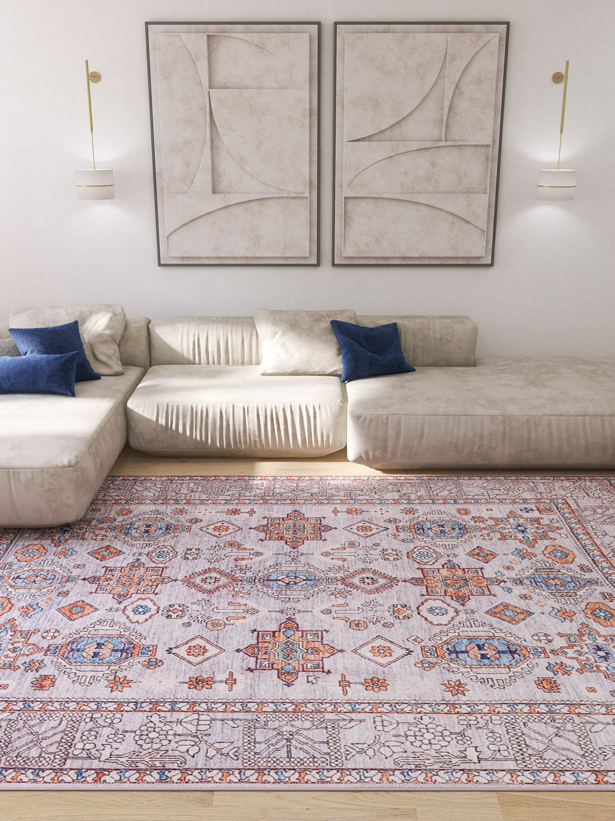 A modern living room with a cream sectional sofa, blue pillows, the Echelon Bordered Washable Rug - LCC3018 in gray-anthracite for high-traffic areas, abstract wall art, and wall-mounted light fixtures.
