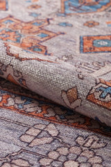 A close-up of the Echelon Bordered Washable Rug - LCC3018, featuring intricate geometric and floral designs in grey, orange, and blue hues; perfect for high-traffic areas with a slightly folded edge shown.