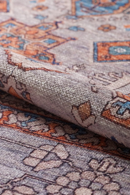 Bild 1 in Galerieansicht laden. A close-up of the Echelon Bordered Washable Rug - LCC3018, featuring intricate geometric and floral designs in grey, orange, and blue hues; perfect for high-traffic areas with a slightly folded edge shown.