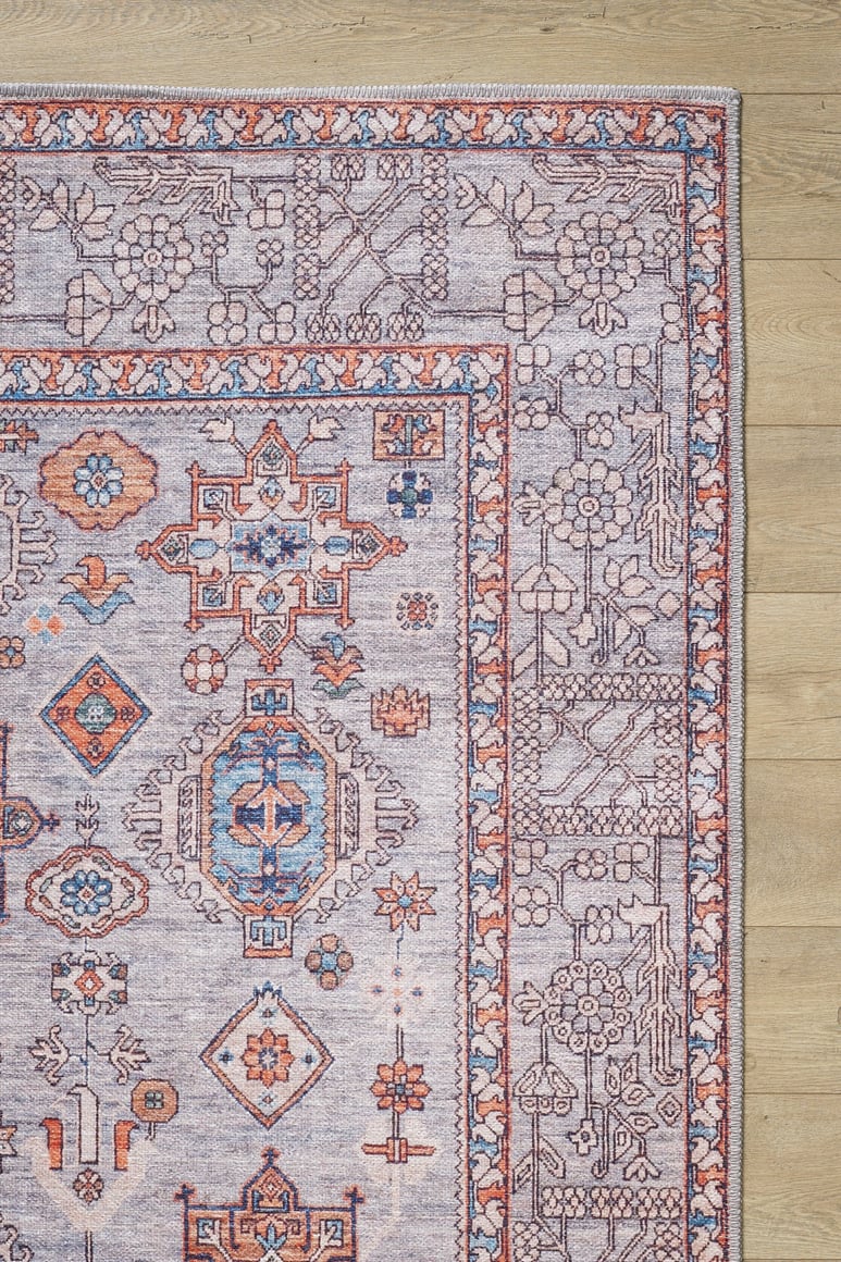 The Echelon Bordered Washable Rug - LCC3018 (Custom Size) features intricate blue, orange, and cream geometric and floral patterns on a light wooden floor—perfect for high-traffic areas.