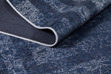 A close-up of the Elegant and Modern - Washable Rug - JR1297 (Custom Size) in blue with white abstract designs and a stitched edge, partially folded to reveal its textured dark underside—ideal for high-traffic areas.