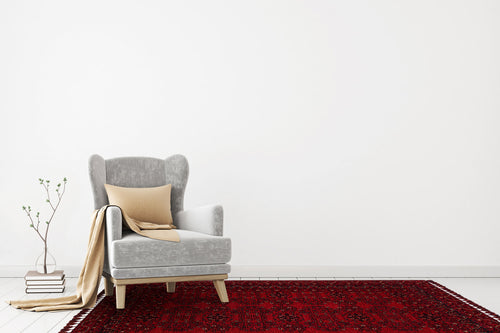 Load image 1 in gallery view. A gray armchair with a beige pillow and throw sits on the Ember Stitch - Washable Kilim - BHR02 rug in a minimalistic room. A small stack of books and a plant are placed on the floor beside the chair.