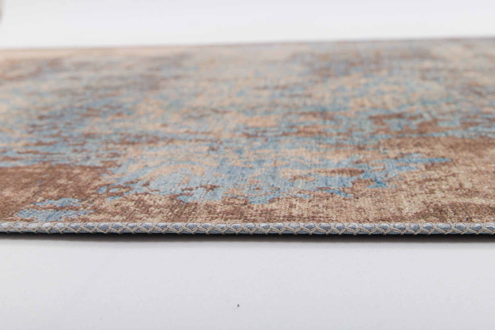Close-up of the Enchanted Threads - Washable Rug - JRS002 (Custom Size), showing its faded blue and brown design and detailed stitching—ideal for high-traffic areas—displayed on a white surface.