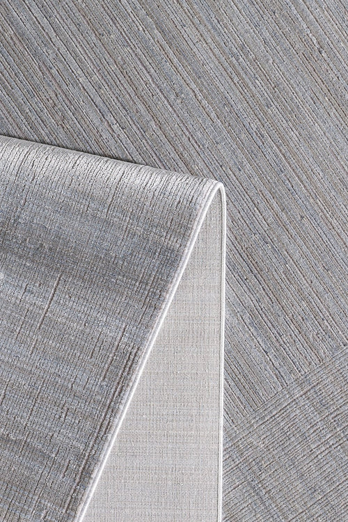 Load image 1 in gallery view. A close-up of the Essential Weave Modern Grey Rug - EW2836 (Outlet) US shows its minimalist design with subtle diagonal lines. One corner is flipped, revealing the underside and white edge trim against a matching patterned background.