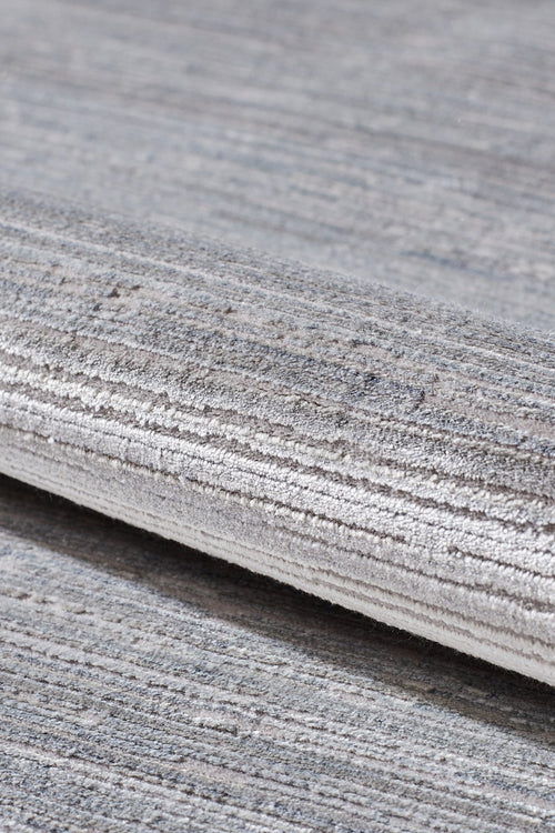 Load image 1 in gallery view. A close-up of the Essential Weave Modern Grey Rug - EW2836 (Outlet) US, machine-made with grey and beige horizontal linear patterns, shown rolled on a matching carpeted floor.