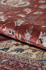 A close-up of the Ethereal Garden Medallion Rug - Burgundy - 2222A, rolled up to show intricate floral designs in red, cream, blue, and gold. The detailed texture of this machine-made rug is visible on both layers.