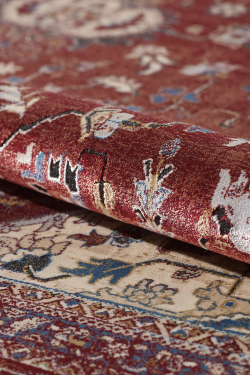 Load image 1 in gallery view. A close-up of the Ethereal Garden Medallion Rug - Burgundy - 2222A, rolled up to show intricate floral designs in red, cream, blue, and gold. The detailed texture of this machine-made rug is visible on both layers.