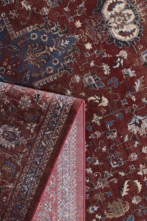 Load image 1 in gallery view. The Ethereal Garden Medallion Rug - Burgundy - 2222A features intricate cream and tan floral and geometric patterns on a richly patterned burgundy and blue background, with a corner folded to reveal its detailed underside and border.