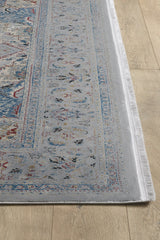 A close-up of the Ethereal Garden Medallion Rug - Grey - 2222C, showcasing its intricate traditional patterns in light blue, grey, and red on a light wood floor. This machine-made rug features fringed edges for added detail.
