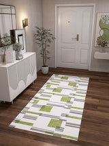 A modern hallway with wood flooring, the Faded Treasure - Washable Rug - JRN46 (Custom Size) in green and black geometric accents, a white sideboard, potted plant, wall art, and a white door—perfect for stylish high-traffic spaces.