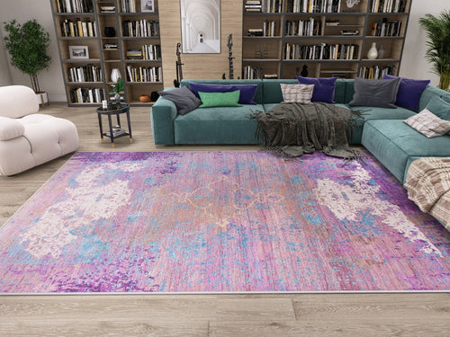 Load image 1 in gallery view. A modern living room features a teal sectional, white armchair, bookshelves, and the Faerie Weave - Washable Rug - JRS005 (Custom Size) in purple—perfect for high-traffic areas. Light wood floors, green plants, and throw pillows add color.