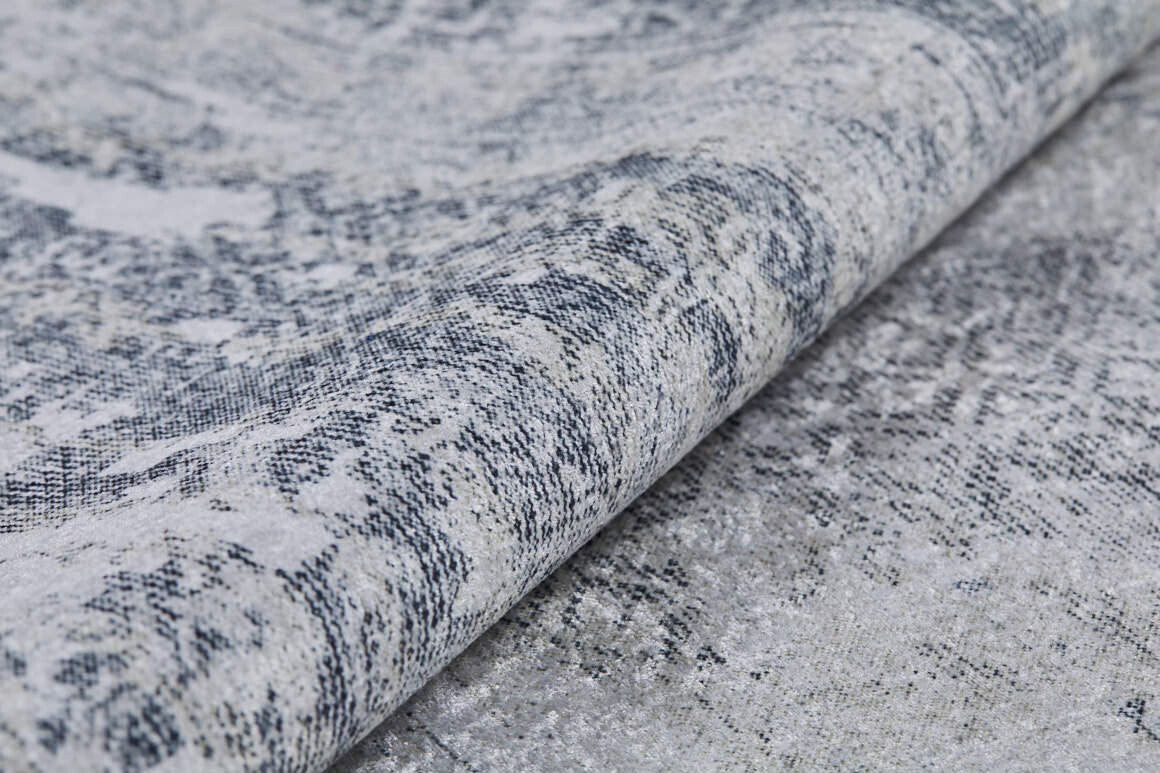 Close-up of the Faint Memories - Washable Rug - JR1437 (Custom Size) in gray and white, featuring a textured, patterned surface with a folded edge and an intricate distressed design.