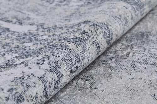Load image 1 in gallery view. Close-up of the Faint Memories - Washable Rug - JR1437 (Custom Size) in gray and white, featuring a textured, patterned surface with a folded edge and an intricate distressed design.