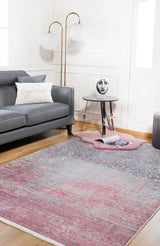 A modern living room with a gray sofa, a “happiness” pillow, and the Floral Filigree - Washable Rug - JR341 (Custom Size)—perfect for high-traffic areas—plus a small round table, decorative face vase, globe floor lamp, and magazine on the rug.