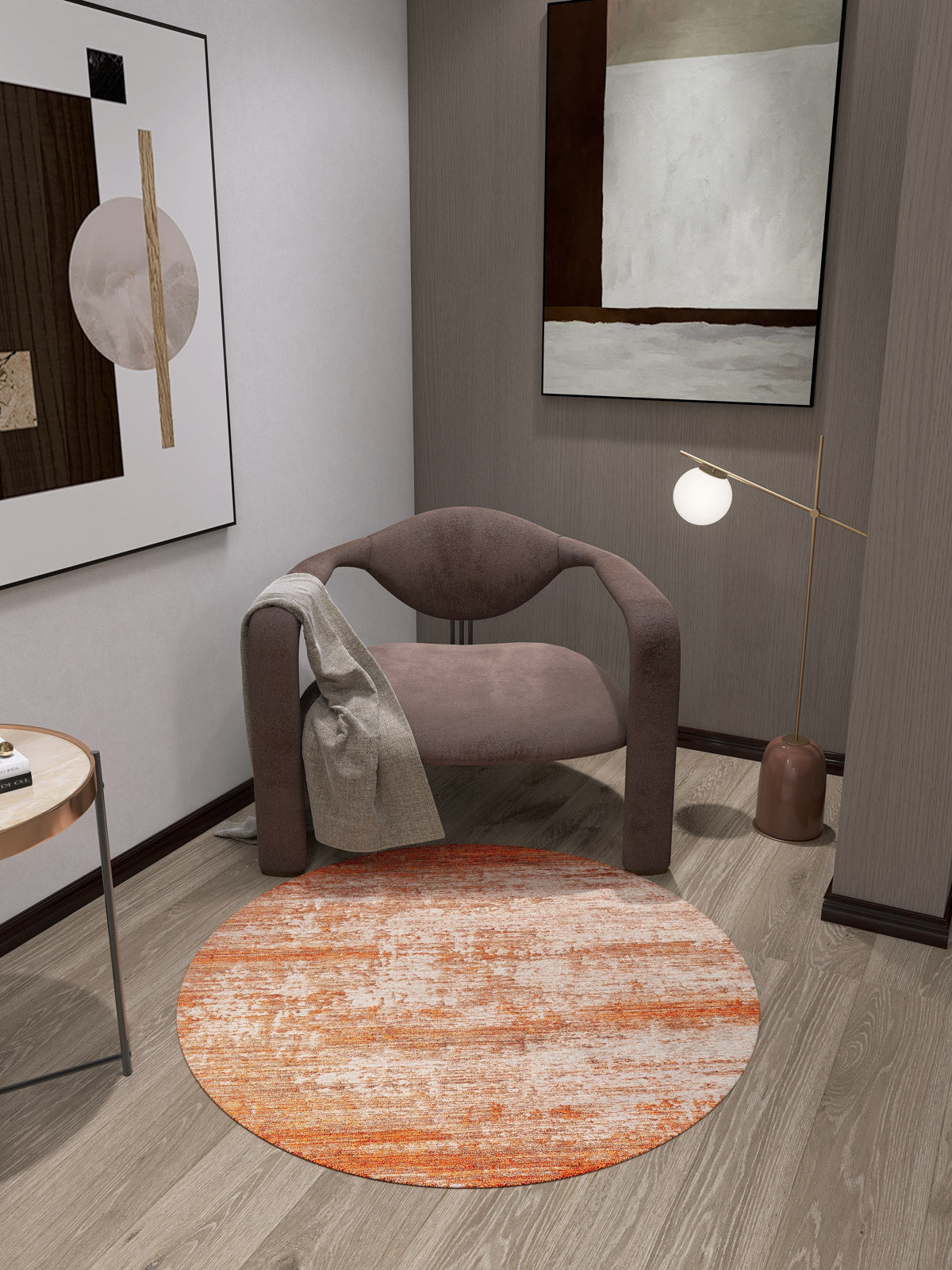 A modern, minimalist room features a curved brown chair with a light gray blanket, abstract wall art, round-bulb floor lamp, small side table, and the Fluffy Brushed - Washable Rug - JR584 (Custom Size) in orange and white for high-traffic areas.