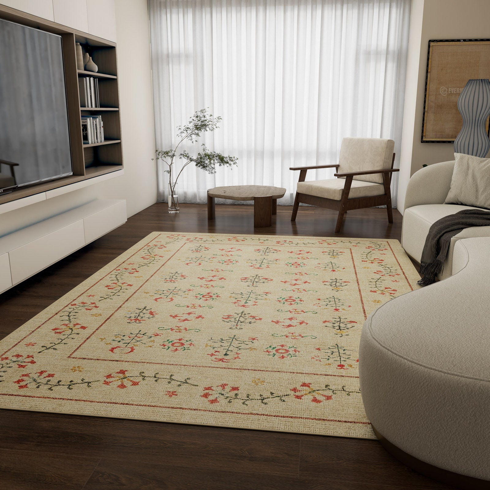 A modern living room with dark wood floors, the Garden Cream - Washable Rug - JRN1026, a white sofa, an armchair, round wooden tables, built-in shelves, a TV, a potted plant, and sheer curtains over large windows.